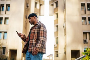 Sokakta cep telefonuyla yürüyen çekici, kendine güvenen bir Afrikalı.