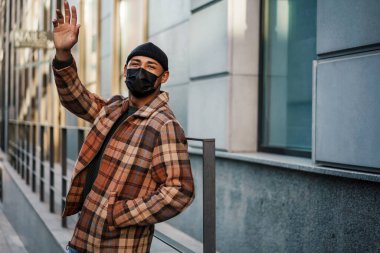 Kendini koronavirüsten korumak için sokakta maske takan yakışıklı bir genç.