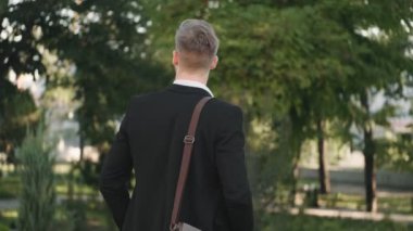 Genç bir iş adamının arka planı parkta yürüyor.