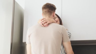 Genç bir çiftin arka plan görüntüsü. Kadın ve erkek evlerinin mutfağında birbirlerine sarılıyorlar.