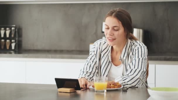 Attraktiv Ung Kvinna Äter Frukost Medan Tittar Tablett Köket Hemma — Stockvideo