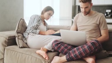 Yoğunlaşmış genç bir çift evdeki kanepede oturuyor.