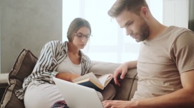 Odaklanmış genç bir çift evdeki kanepede oturuyor.