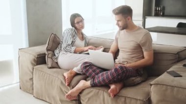 Çekici genç bir çift kanepede oturuyor ve evlerinde iletişim kuruyorlar.