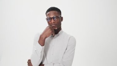 Gözlük takan ciddi bir Afrikalı Amerikalı, stüdyoda beyaz arka planda tek başına duran parmaklarına güveniyor.