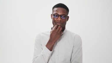 Gözlüklü Afro-Amerikalı bir adam beyaz arka planda, stüdyoda izole edilmiş bir şey düşünüyor.