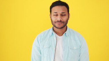 Oyuncu bir Hintli farklı yüz ifadeleri gösteriyor. Stüdyoda sarı arka planda duruyor.