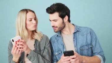 Yakışıklı bir adam, kız arkadaşının telefonuna göz kulak olurken o da stüdyonun mavi arka planında tek başına duran bir mesaj yazıyor.