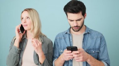 Çok hoş bir kadın, erkek arkadaşı stüdyonun mavi arka planında tek başına sohbet ederken akıllı telefondan konuşuyor.