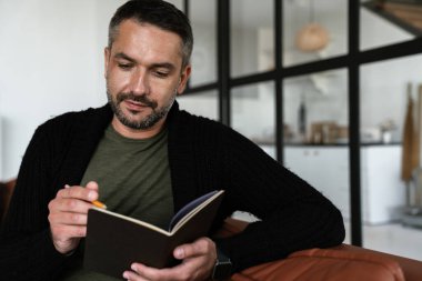 Modern ofiste otururken notlar alan kendinden emin genç bir iş adamı.