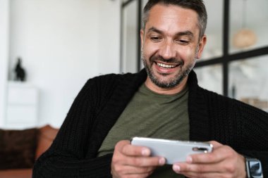 Ofiste dururken cep telefonu kullanan çekici, kendine güvenen genç bir iş adamı.