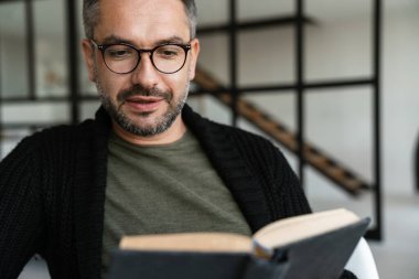 Ofiste kitap okuyan kendinden emin genç bir işadamı.