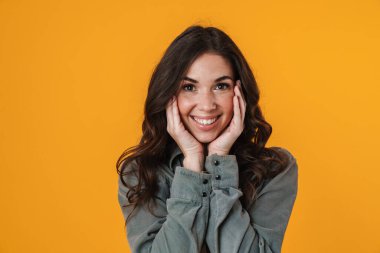 Sarı arka planda izole edilmiş neşeli, güzel kız poz veriyor ve gülümsüyor.