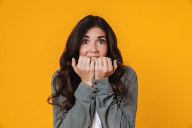 Korkak güzel kız poz veriyor ve sarı arka planda izole edilmiş kameraya bakıyor.