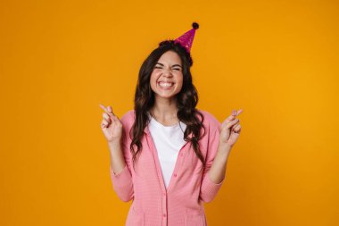 İyi şans dilemek için sarı arka planda poz veren mutlu güzel kız.