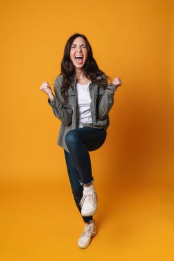Heyecanlı güzel kız sarı arka planda izole edilmiş güzel hareketler ve çığlıklar yapıyor.