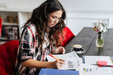 Kafede kahve içerken gazetelerle yazıp çalışan hoş bir kadın.