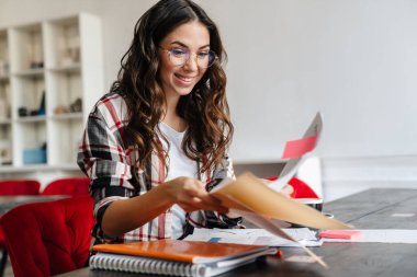 İçeride masa başında ders çalışan mutlu genç kız öğrenci.