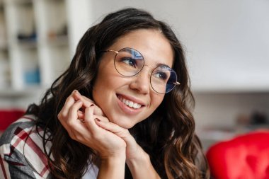 Gözlüklü hoş bir kadın gülümsüyor ve içeri bakıyor.