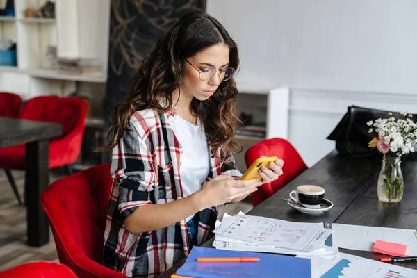 Seriös Trevlig Kvinna Som Använder Mobiltelefon Och Arbetar Med Papper — Stockfoto