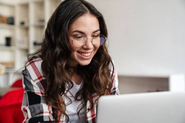 Gülümseyen ve kafede otururken dizüstü bilgisayarla çalışan mutlu bir kadın.