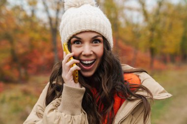 mutlu genç kadın cep telefonuyla sonbahar park