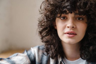 Kapalı alanda gülümseyen çekici bir genç kadının yakın plan portresi.