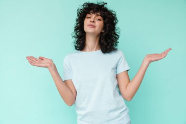 Neşeli, güzel, kıvırcık kız gülümseyen ve kopyalama alanını mavi arka planda tutan.