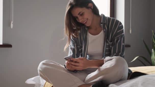 Задоволена Молода Жінка Використовує Свій Смартфон Сидячи Спальні Вдома — стокове відео