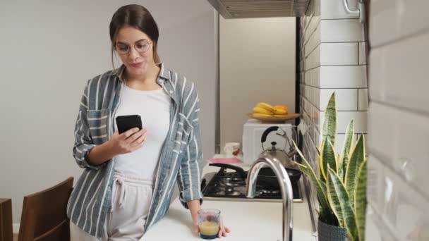 Uma Jovem Sorrindo Usando Óculos Está Usando Seu Smartphone Enquanto — Vídeo de Stock