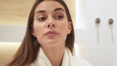 Genç ve güzel bir kadın apartmandaki aynaya bakıyor.