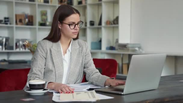 Poważna Młoda Bizneswoman Okularach Pracuje Papierowymi Dokumentami Jej Laptop Siedzi — Wideo stockowe