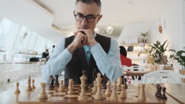 Yakışıklı bir adamın yakından çekilmiş görüntüsü içeride satranç oynuyor.