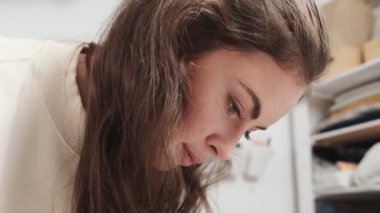 Dizayn stüdyosunda çalışan konsantre genç bir kadın terzinin yakın çekim görüntüsü