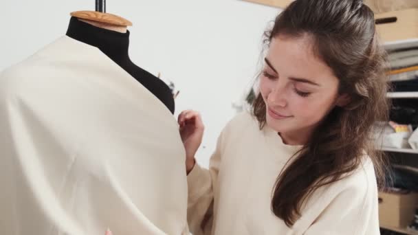 Μια Χαρούμενη Νεαρή Μοδίστρα Διορθώνει Δείγμα Του Φορέματος Που Δουλεύει — Αρχείο Βίντεο