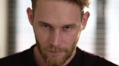 Gülümseyen genç bir adam evde kameraya poz veriyor.