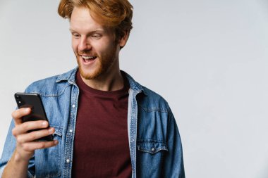 Beyaz arka planda izole edilmiş cep telefonu kullanırken gülümseyen heyecanlı beyaz saçlı adam.