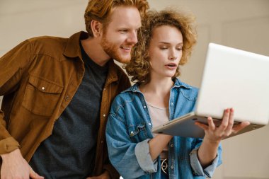 İş ortakları ofiste dururken dizüstü bilgisayarda çalışıyor.