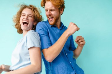 Mavi arka planda dans eden mutlu ve mutlu bir çift genç adam ve kadın.