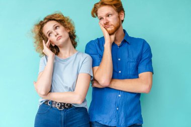 Sıkıcı genç çift mavi arka planda tek başına duruyor.