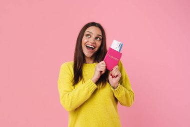 Pasaport ve biletlerle poz verirken gülümseyen mutlu esmer kız.