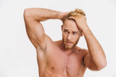 Beyaz arka planda yalnız bırakılmış beyaz gömleksiz yakışıklı bir adam poz veriyor.