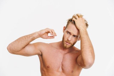 Beyaz arka planda yalnız bırakılmış beyaz gömleksiz yakışıklı bir adam poz veriyor.