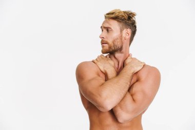 Beyaz arka planda yalnız bırakılmış beyaz gömleksiz yakışıklı bir adam poz veriyor.