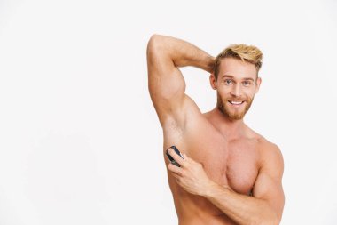 Beyaz arka planda izole edilmiş deodorant kullanırken gülümseyen beyaz gömlekli, beyaz bir adam.