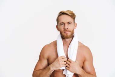 Beyaz arka planda izole edilmiş kameraya havluyla poz veren beyaz, beyaz, beyaz, üstsüz bir adam.