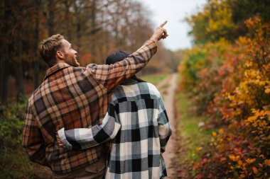 Güzel mutlu çift, sonbahar ormanlarında dolaşırken bir kenara çekilip sarılıyor.