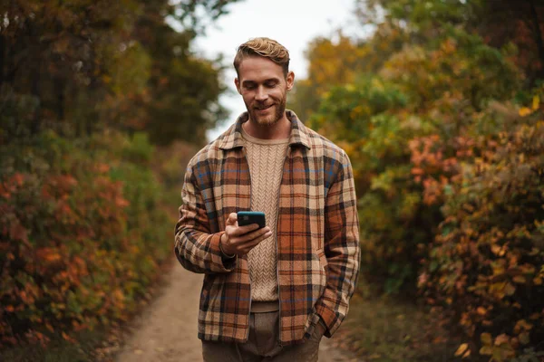 Joyful Unshaven Man Using Mobile Phone While Strolling Autumn Forest — Stock Photo, Image