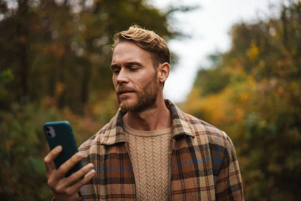 Handsome Unshaven Man Using Mobile Phone While Strolling Autumn Forest — Stock Photo, Image