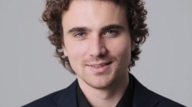 A close-up view of a happy man is smiling to the camera standing isolated over gray wall in the studio
